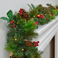 Pre lit Christmas garland with green pine branches, warm white LED lights, holly leaves, red berries and large pine cones